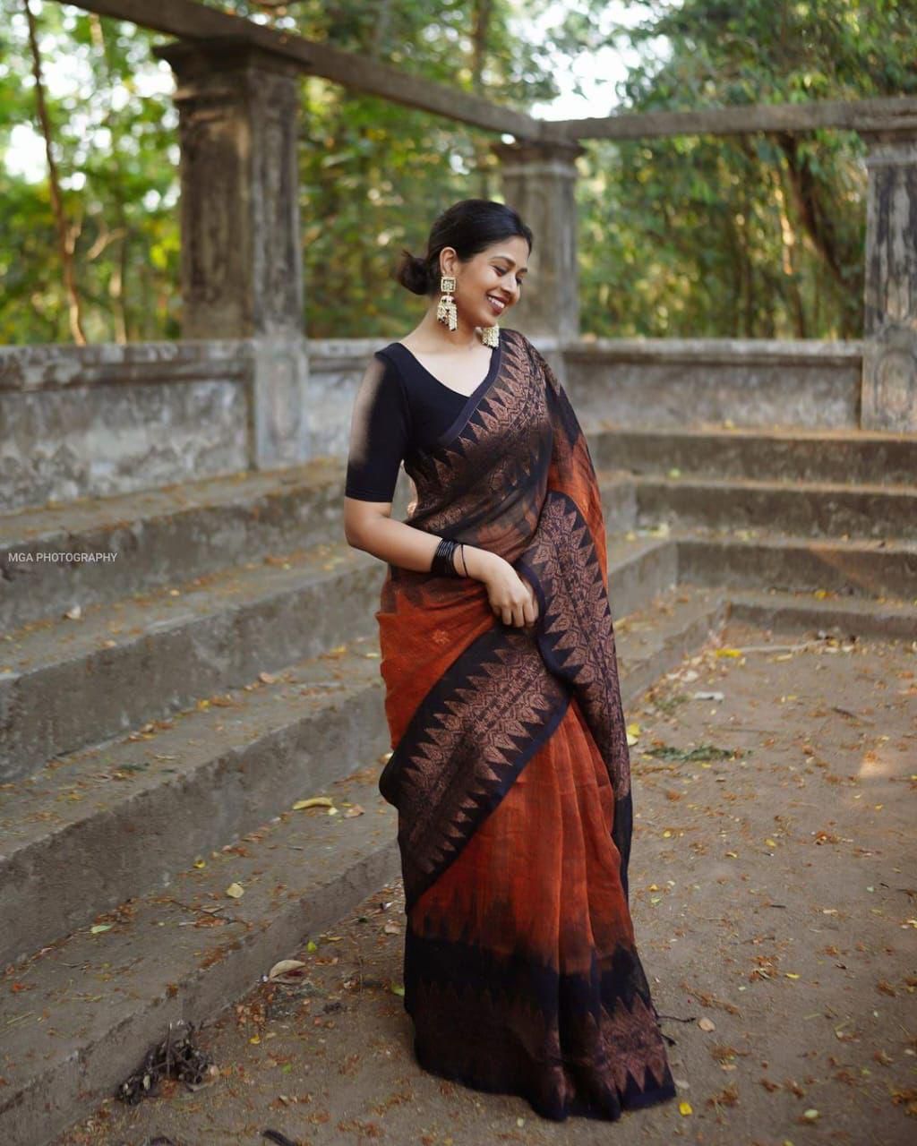 Woman wearing a premium brown saree for women with black blouse and traditional earrings outdoors